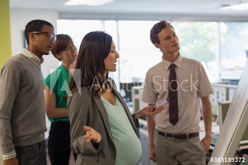 Pregnant businesswoman and colleagues brainstorming in office