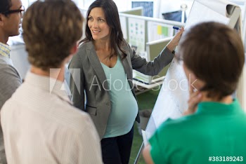 Pregnant businesswoman at flipchart leading meeting in office
