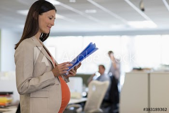 Pregnant businesswoman reading paperwork in office