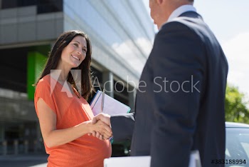 Pregnant businesswoman shaking hands with colleague