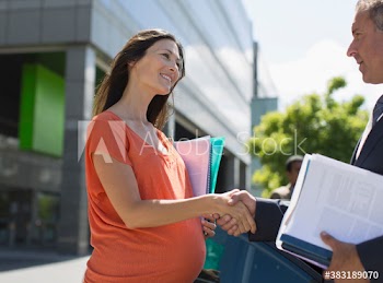 Pregnant businesswoman shaking hands with colleague