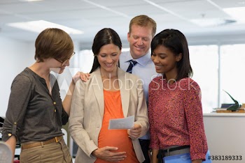 Pregnant businesswoman showing ultrasound with colleagues