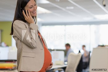 Pregnant businesswoman talking on smart phone in office