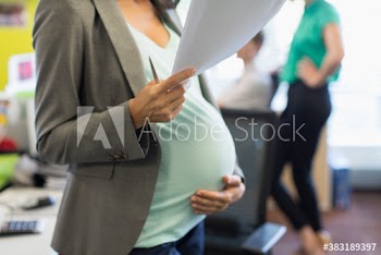 Pregnant businesswoman with paperwork holding stomach