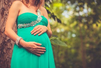 Pregnant Woman in Green One-shoulder Dress Holding Her Belly