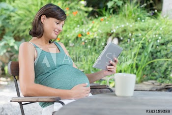 Pregnant woman using digital tablet on patio