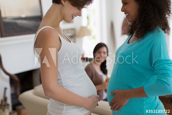 Pregnant women comparing baby bumps