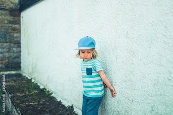 Preschooler up against a white wall outdoors