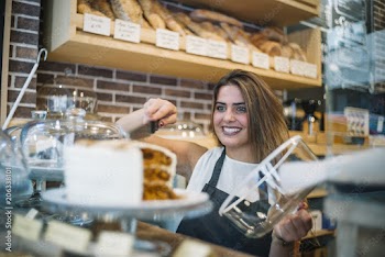 Pretty woman working in bakery cutting cake