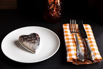 Product Photography of Silver Heart Accessory White Ceramic Plate and Fork and Steak Knife on White and Orange Handkerchief