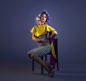 Purple Haired Drag Queen Poses In Chair