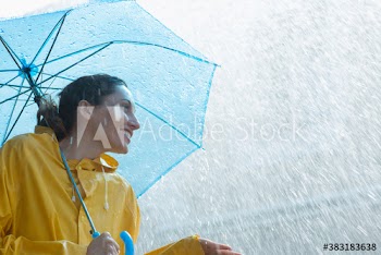 Rain falling over smiling woman with umbrella