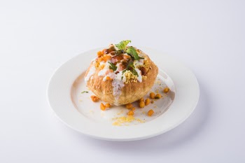 Rajasthani Shahi Raj-Kachori, stuffed with potato and sprout filling. served with curd, chutney and sev in a plate, isolated over colourful or wooden background. selective focus