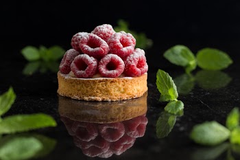 Raspberry tart dessert on dark background. Traditional french sweet pastry. Delicious, appetizing, homemade cake with custard, fresh berries and fruits. Copy space, closeup. Selective focus