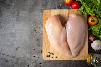 Raw chicken breasts on wooden cutting board. Free Photo
