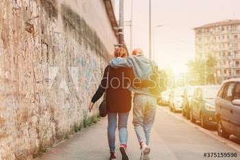 Rear view of friends walking on sidewalk