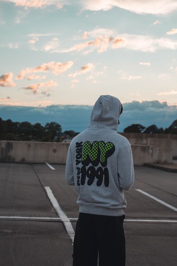 Rear view of Man Wearing Gray Pullover Hoodie and Black Pants at Parking Lot
