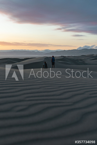 Rear view of people on sand dunes during sunset
