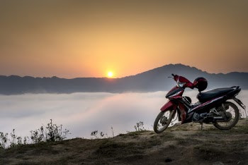 Red and Black Underbone Motorcycle on Mountain Cliff Surrounded by Sea of Clouds