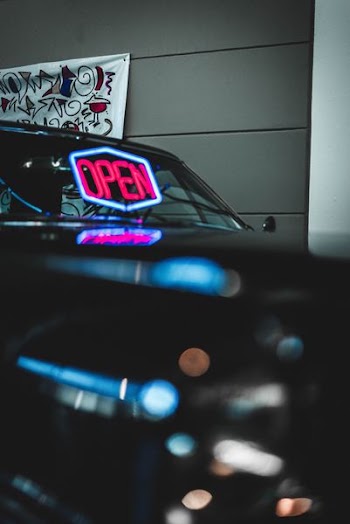 red and blue open neon signage reflecting on vehicle windshield