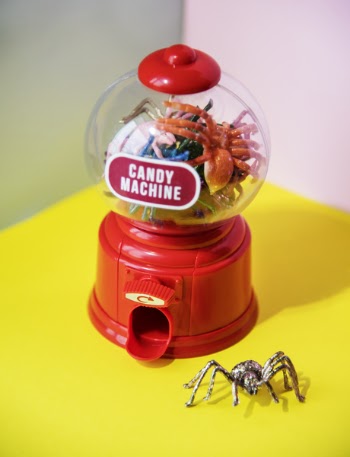 Red and Clear Plastic Candy Machine on Yellow Desk