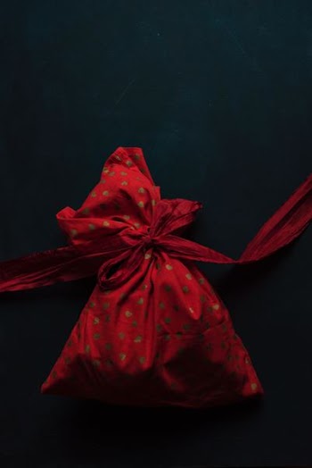 red and gold polka-dot drawstring pack on black surface