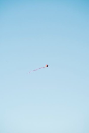 red and white kite flying in the sky