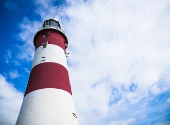 red and white lighthouse under cloudy blue sky