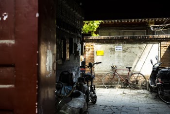 Red Bicycle Parked Besides Brown and White Wall