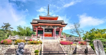 Red Black and White Building Structure Surrounded by Trees Under White Clouds during Daytime