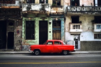 red car parked on road in front concrete building