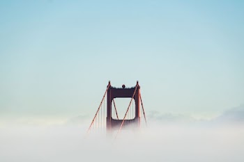 red concrete bridge surrounded by clouds