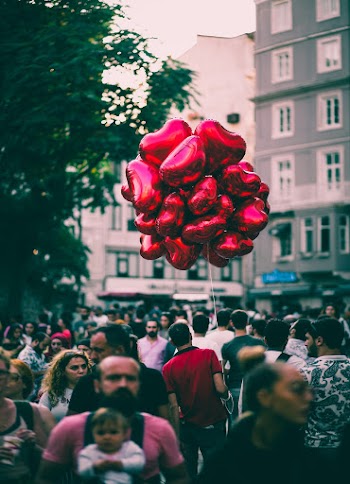 Red Heart Balloons over People Walking on Street