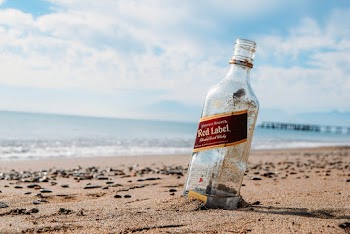 Red Label Glass Bottle on Brown Sand