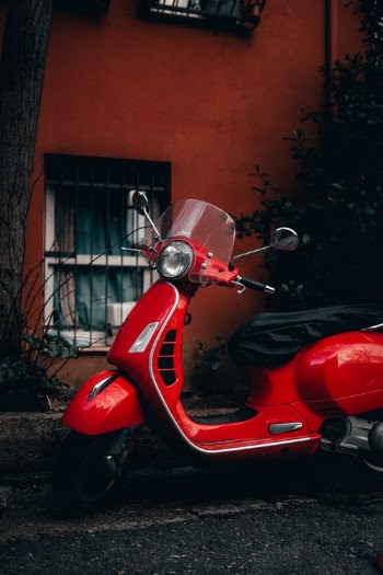 Red Motor Scooter Parked Beside Brown Brick Wall · Free Stock Photo