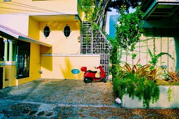 Red Motor Scooter Parked Beside the Beige Concrete Wall