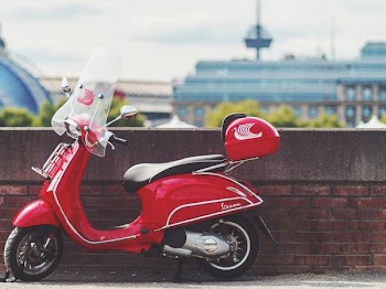 red motor scooter parking near wall