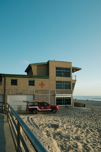 Red Pickup Truck Beside Concrete Building Under Clear Blue Sky