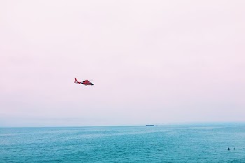 red plane on mid air above sea