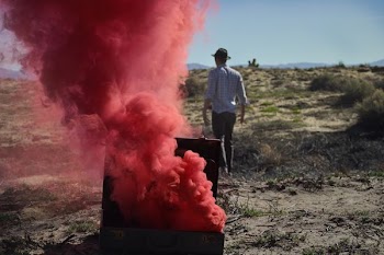 red smoke bomb on chest near man wearing black cap