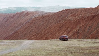 red SUV near the edge of a mountain during day