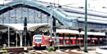 Red Train at a Green Train Station on an Overcast Day