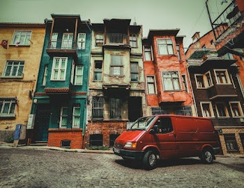 Red Van Parked Beside Brown and Green Concrete Building