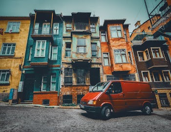 Red Van Parked Near Concrete Buildings