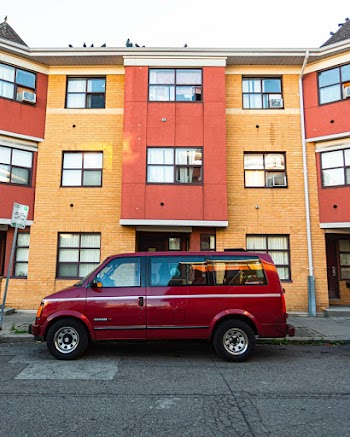 Red Van Parked on Curb Beside Building