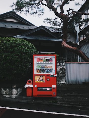 red vending machine beside red plastic trash can