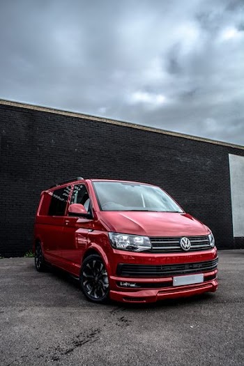 red Volkswagen Caravelle parked beside black cocnrete building