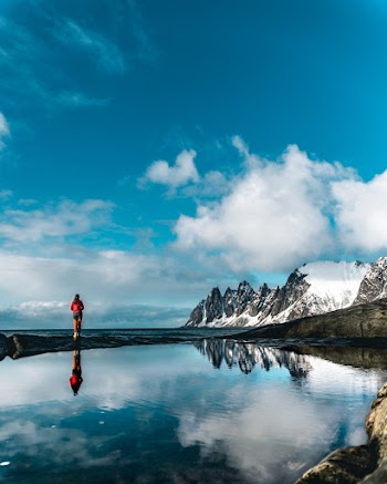 Reflection Of Person In Red Shirt Standing Near Body Of Water