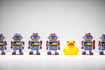 Retro tin toy robots and a rubber duck standing in a row.