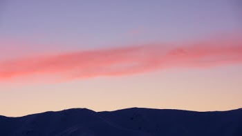 Ribbon of pink cloud above snowy mountains, Saint Bathans, Otago, New Zealand